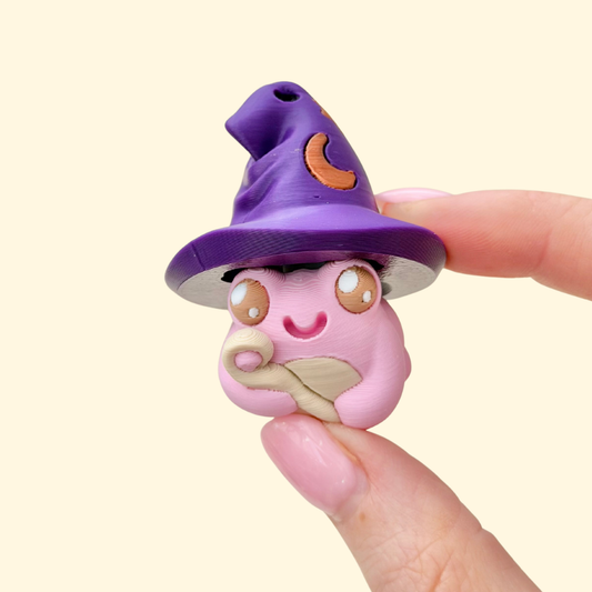 Frog-shaped clicker fidget with witch hat press mechanism for tactile sensory stimulation.
