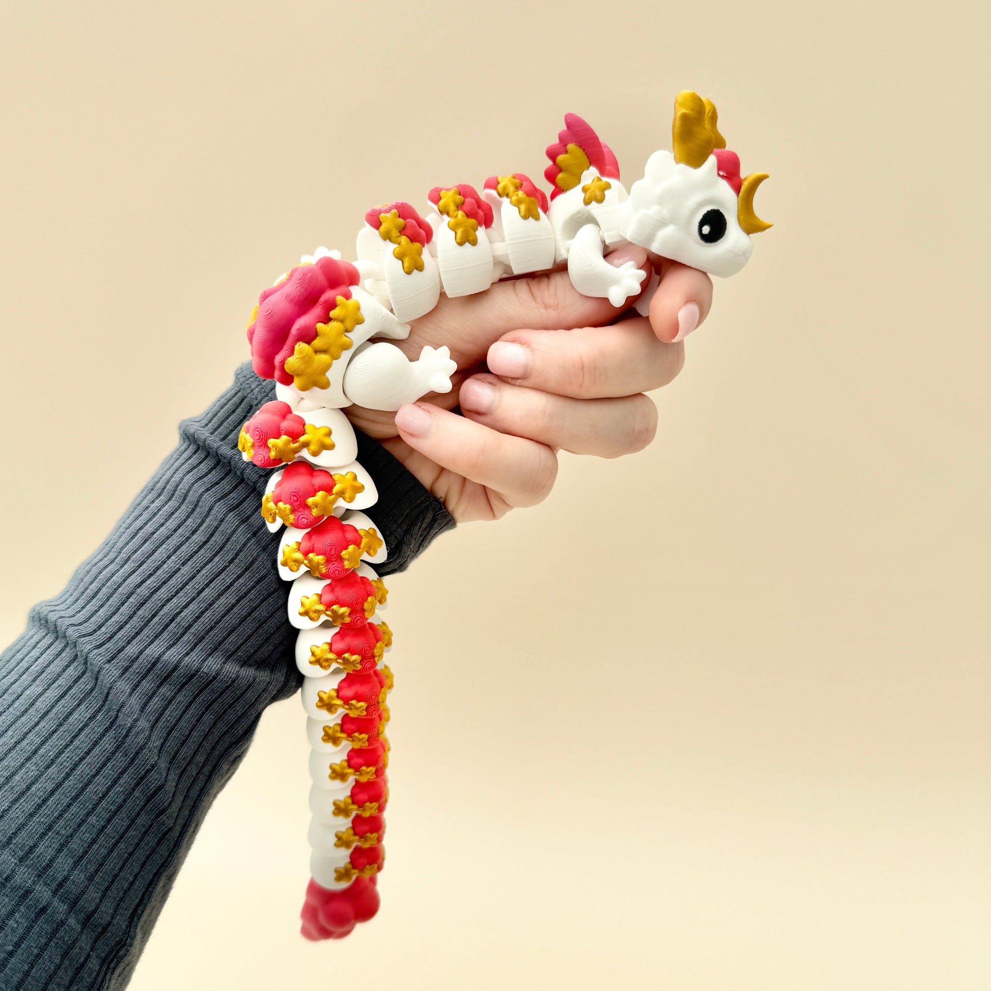 White dragon with gold moon and stars, pink and red accents, and articulated wings and body.