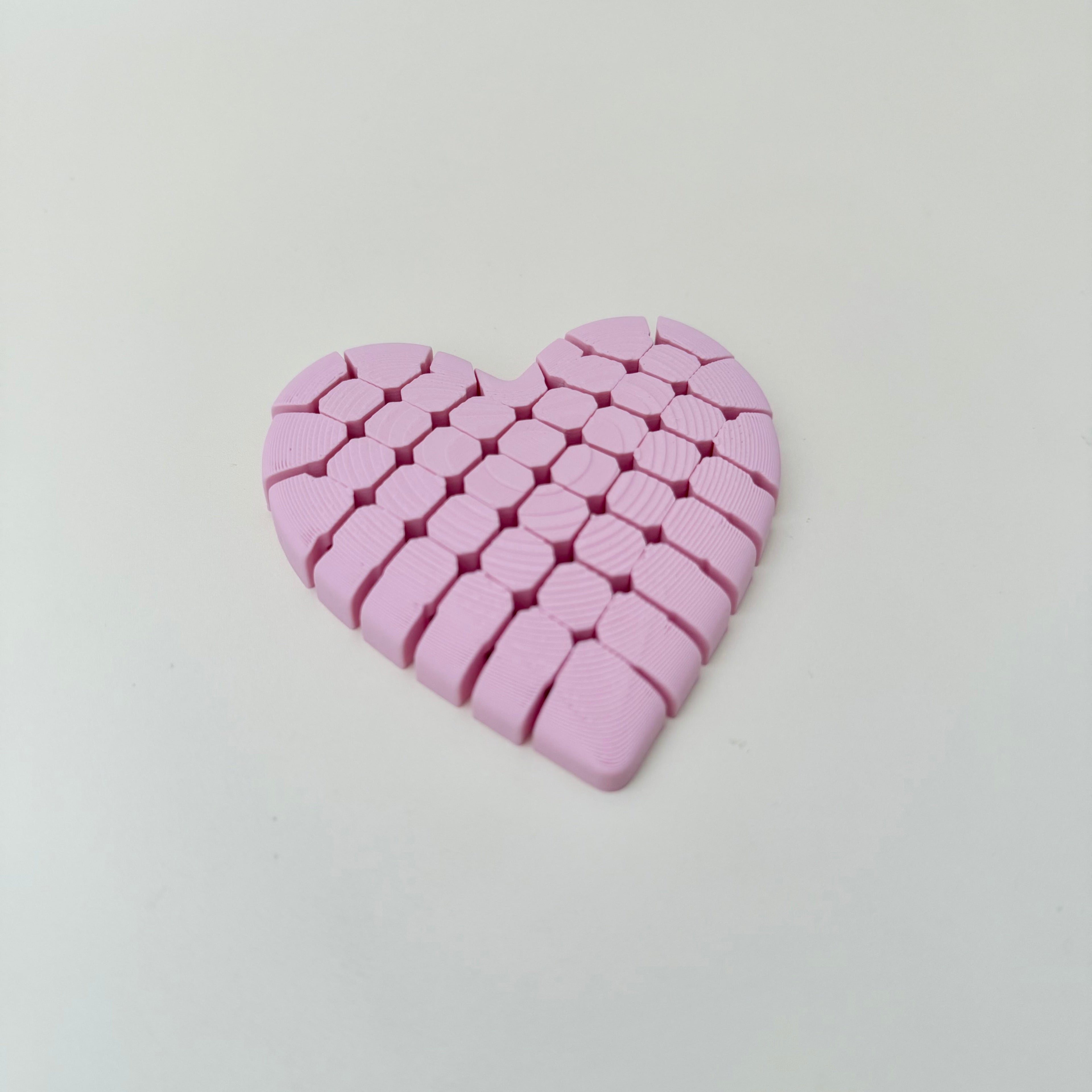 Flexible 3D printed heart fidget with segmented movement and textured underside for stimming and focus.
