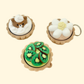 Three dessert-style fidget clickers with realistic tart toppings and keyring attachments.