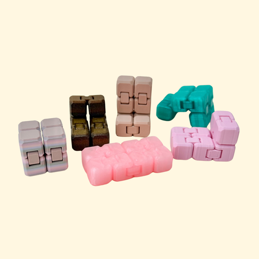 Small articulated cube fidget that flips and folds between shapes for tactile input.
