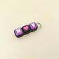 Keychain with 'H U' letters and a pink heart on a beige background