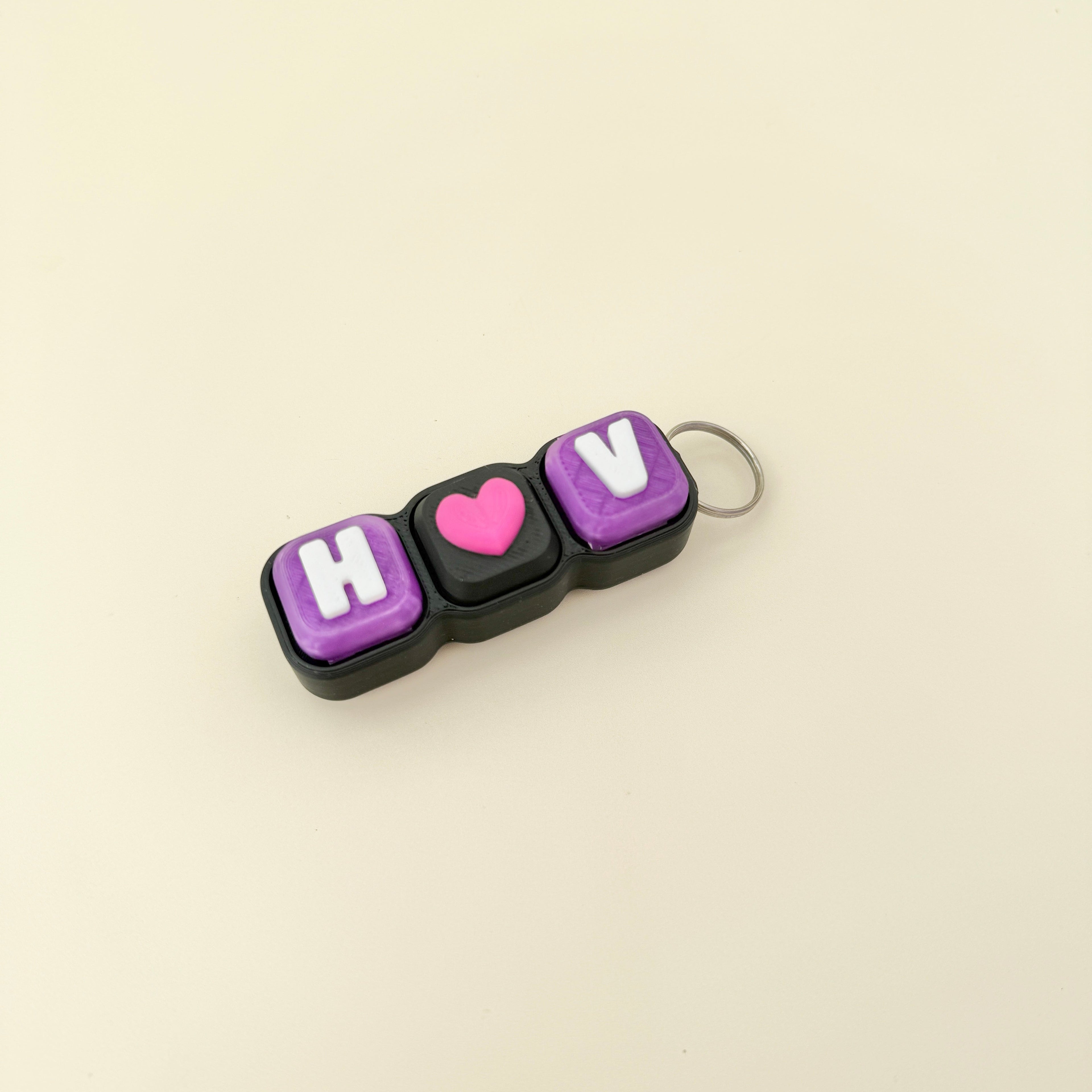 Keychain with 'H U' letters and a pink heart on a beige background