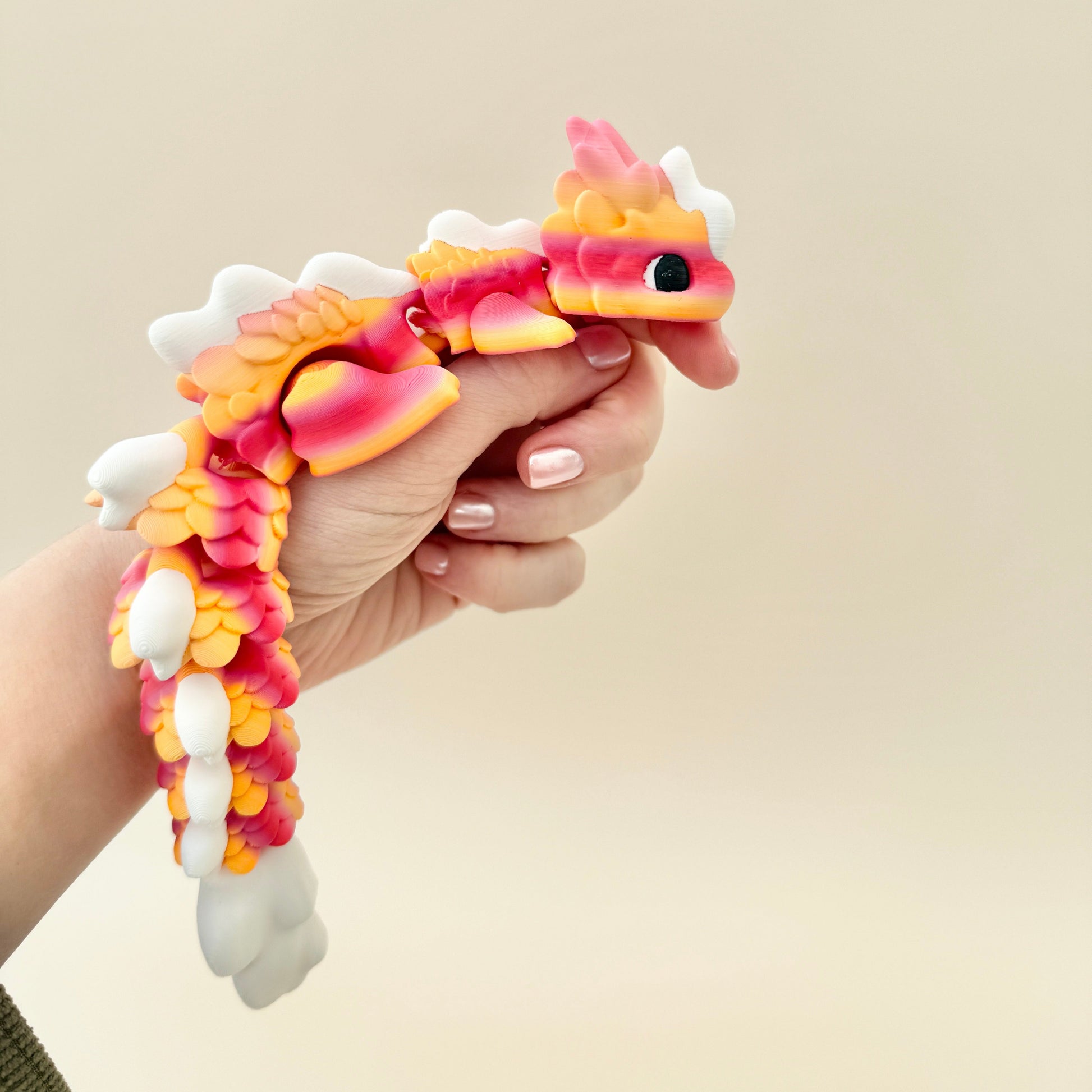 Pastel-inspired Kaida Dragon fidget toy with a white, peach, and pink gradient design and black and white eyes.