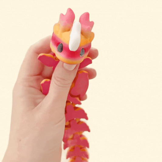 Fully articulated Kaida Scaled Dragon in a soft peach and pink gradient with white features and lifelike black eyes.