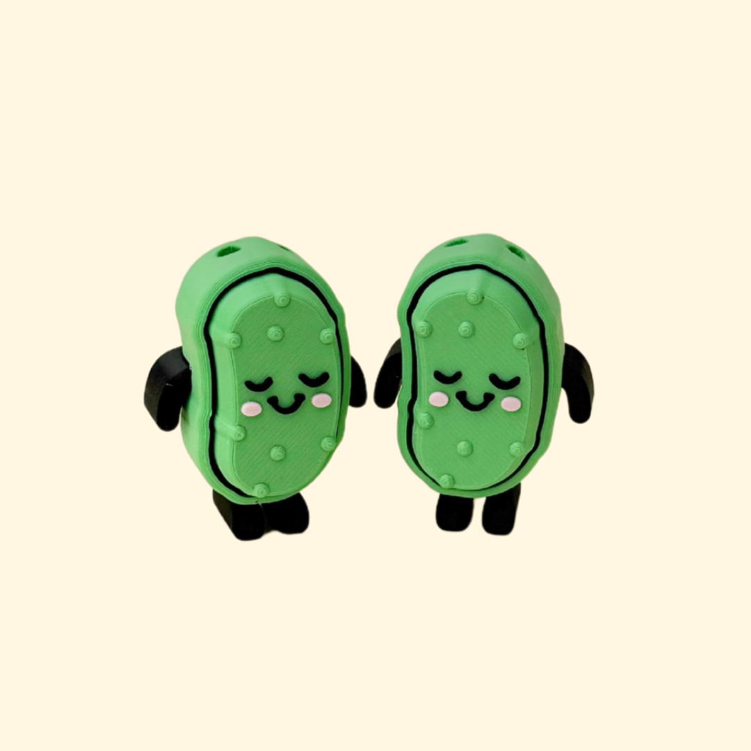 Small pickle-shaped fidget toy with arms, legs, and pressable top for sensory clicking.