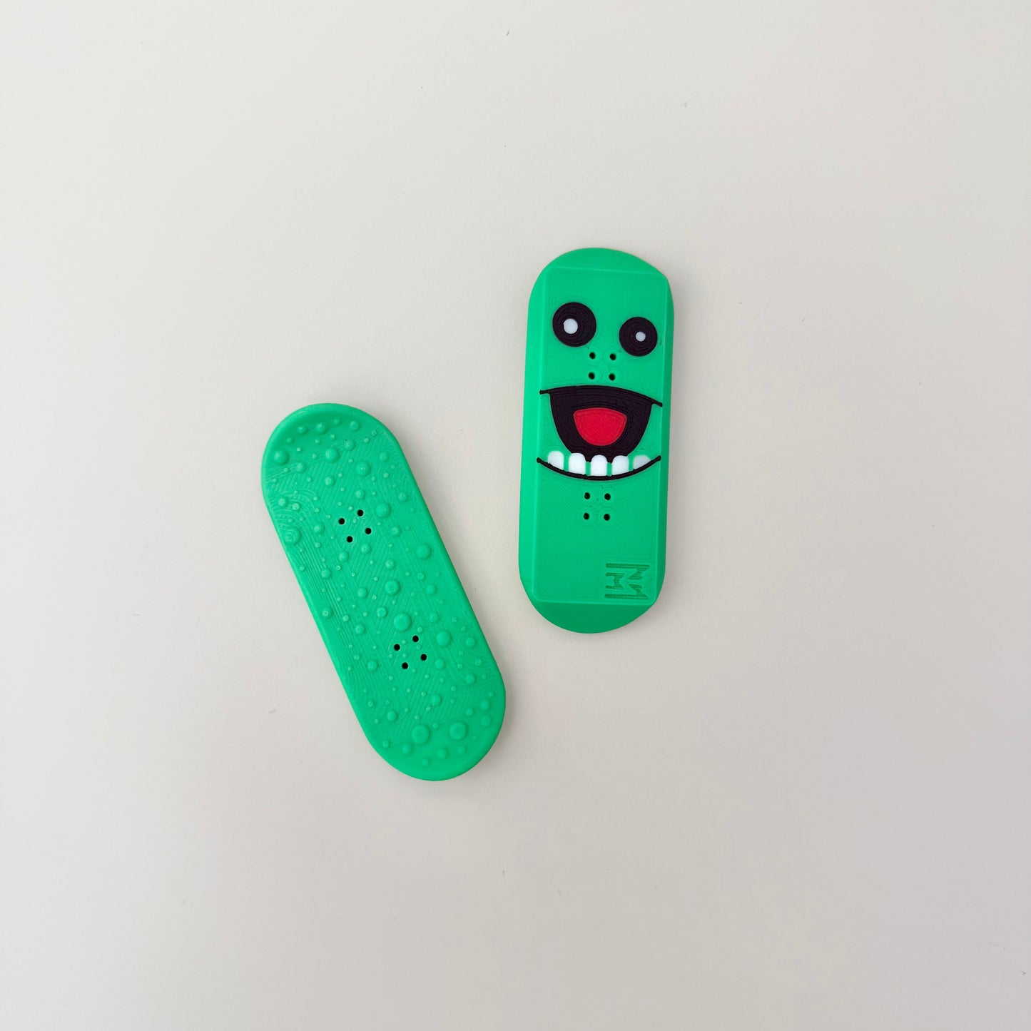 Set of two green pickle-style magnetic fidgets with smooth and textured sides for sensory play.
