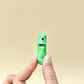 A small, sparkly green pickle toy with interactive features, designed for sensory play.