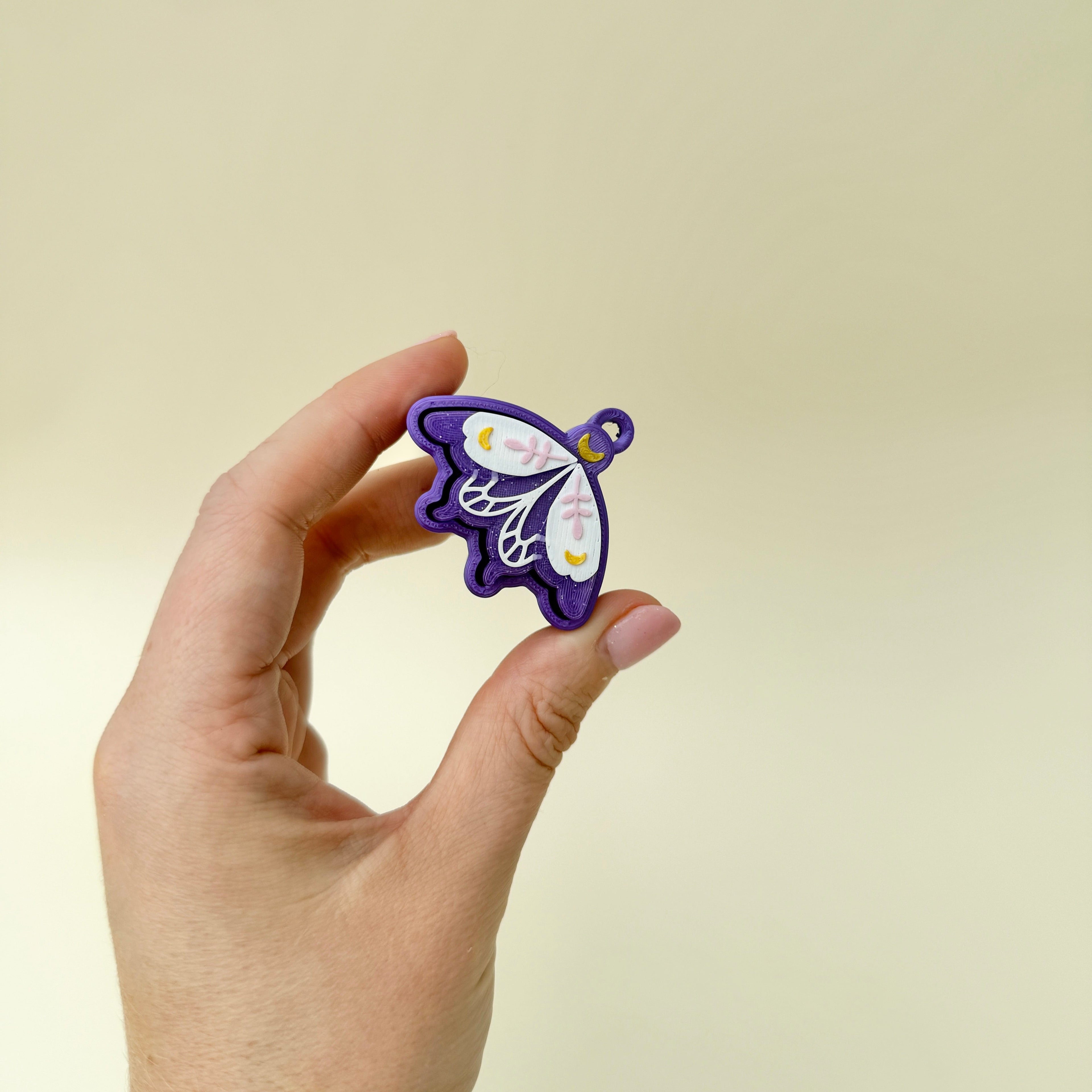 Wing-shaped clicker with white, gold and pink accents, ideal for keyrings or lanyards