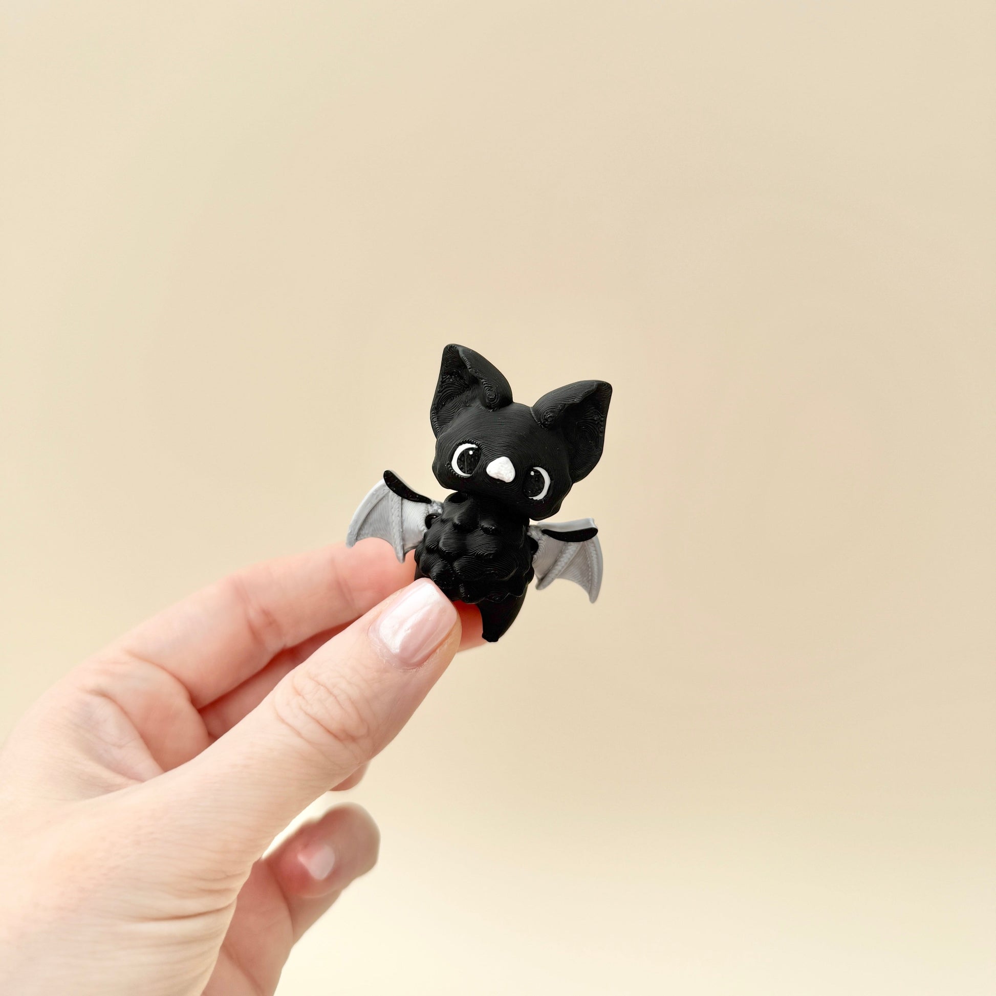 Small black bat fidget toy with moveable wings, ideal for sensory play and stress relief.