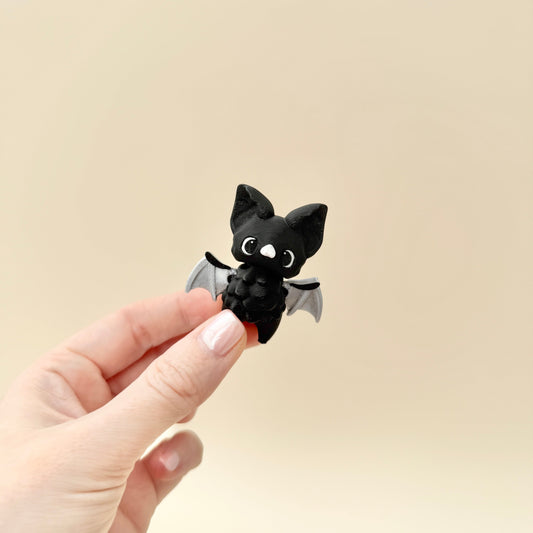 Small black bat fidget toy with moveable wings, ideal for sensory play and stress relief.