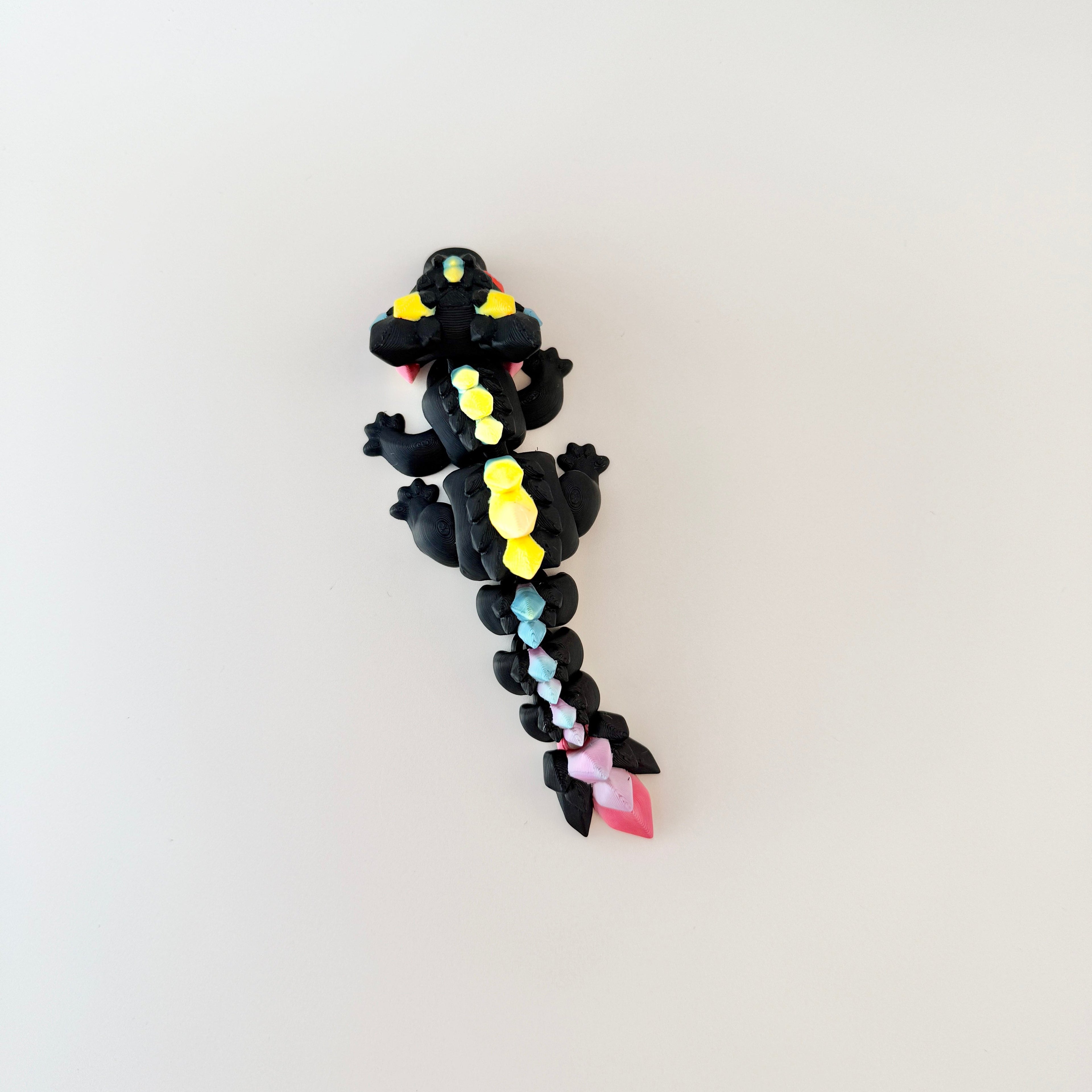 Compact black dragon sensory toy with rainbow details and articulated body, ideal for stress relief.