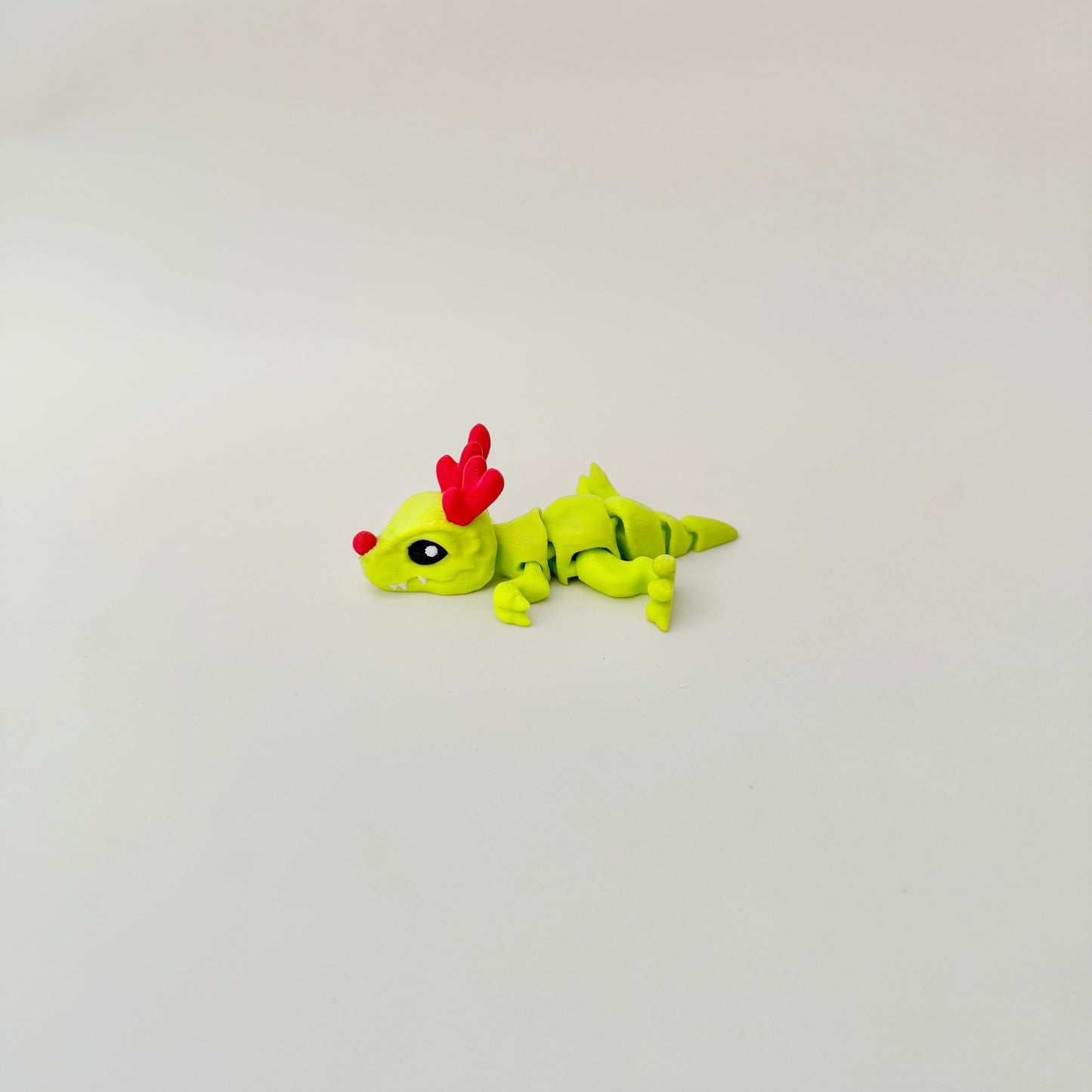 Mini articulated dinosaur fidget toy, stands or lies flat, gentle wiggle motion for calm fidgeting.
