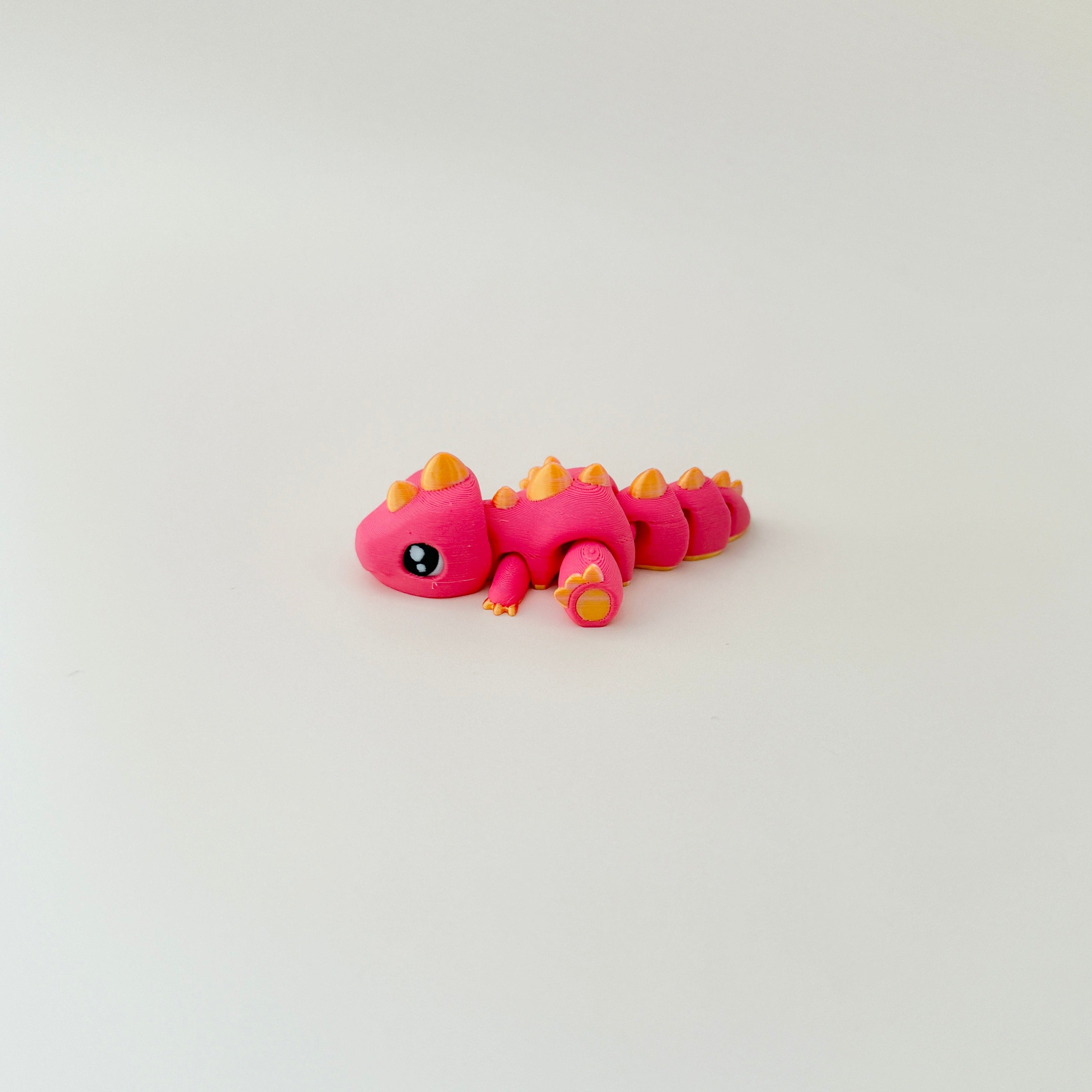 8cm long dinosaur toy with red body, gold spikes, and flexible joints for hands-on fun.
