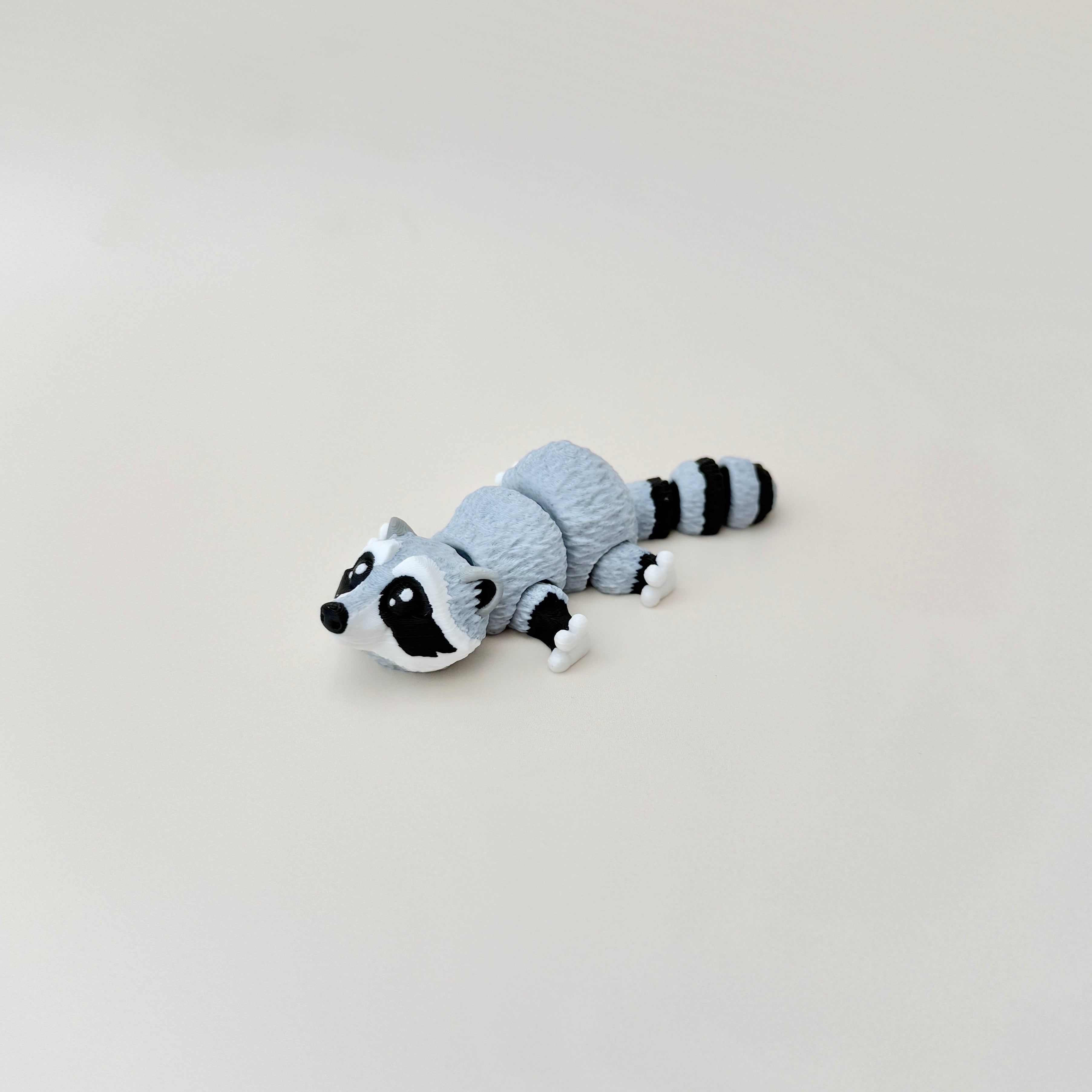 Compact 10cm raccoon fidget toy with lifelike colouring, ideal for stress relief and play.