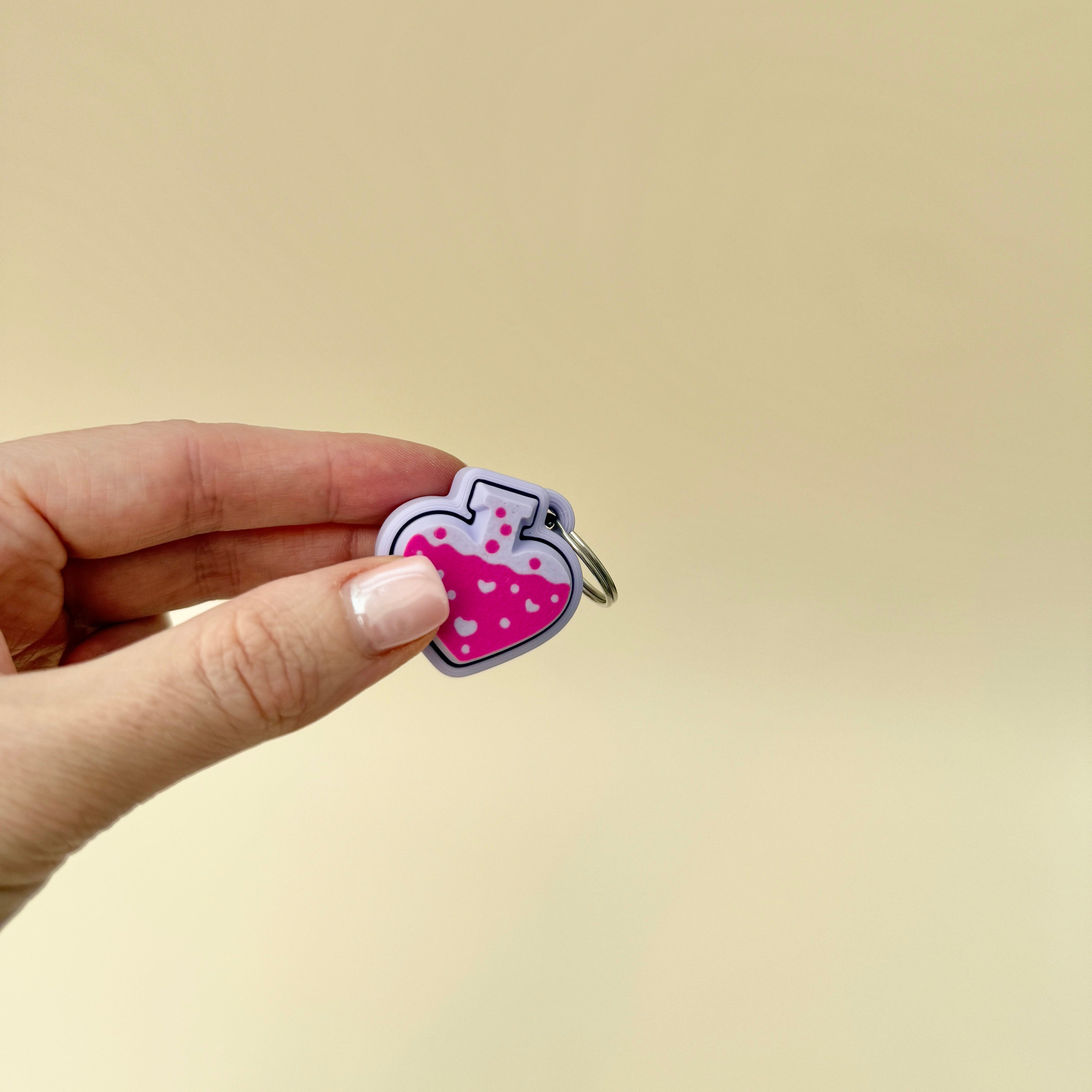 Front view of a potion bottle keyring fidget toy with liquid design and heart accents, available in black or lilac.