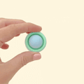 A small, circular fidget clicker with a pressable top, designed for satisfying tactile feedback.