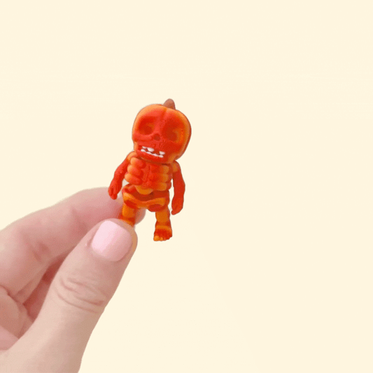 Mini articulated skeleton fidget with pumpkin-style head and gradient orange finish
