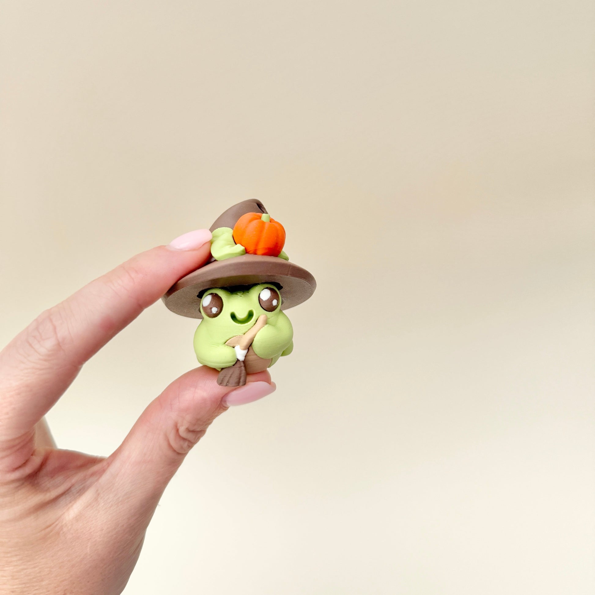 Frog fidget with a pointed hat decorated with a small pumpkin and leaves.
