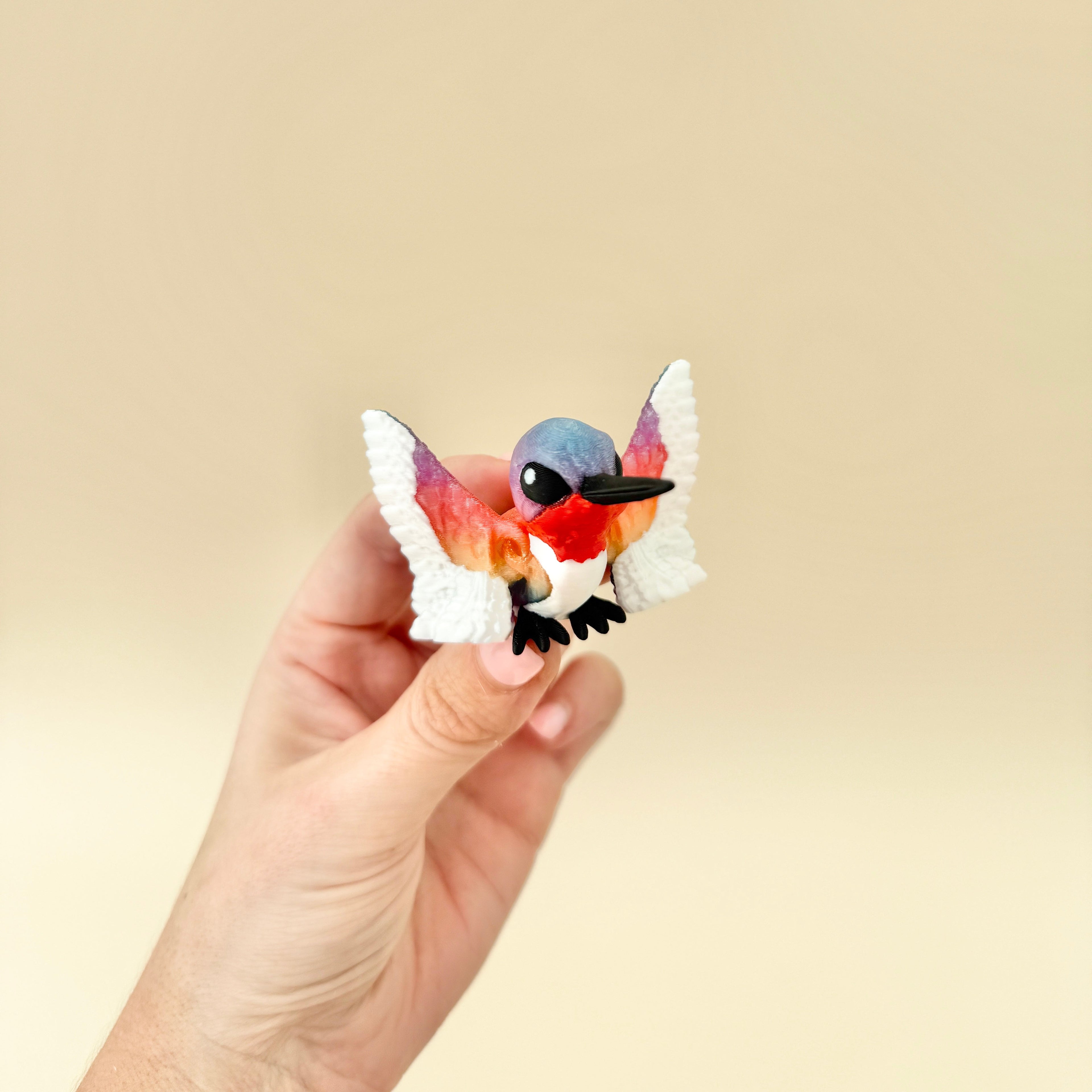 A vibrant, gradient-coloured hummingbird fidget toy with elegant articulation.
