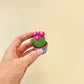 Cute cactus clicker with colourful base and textured surface for tactile feedback.