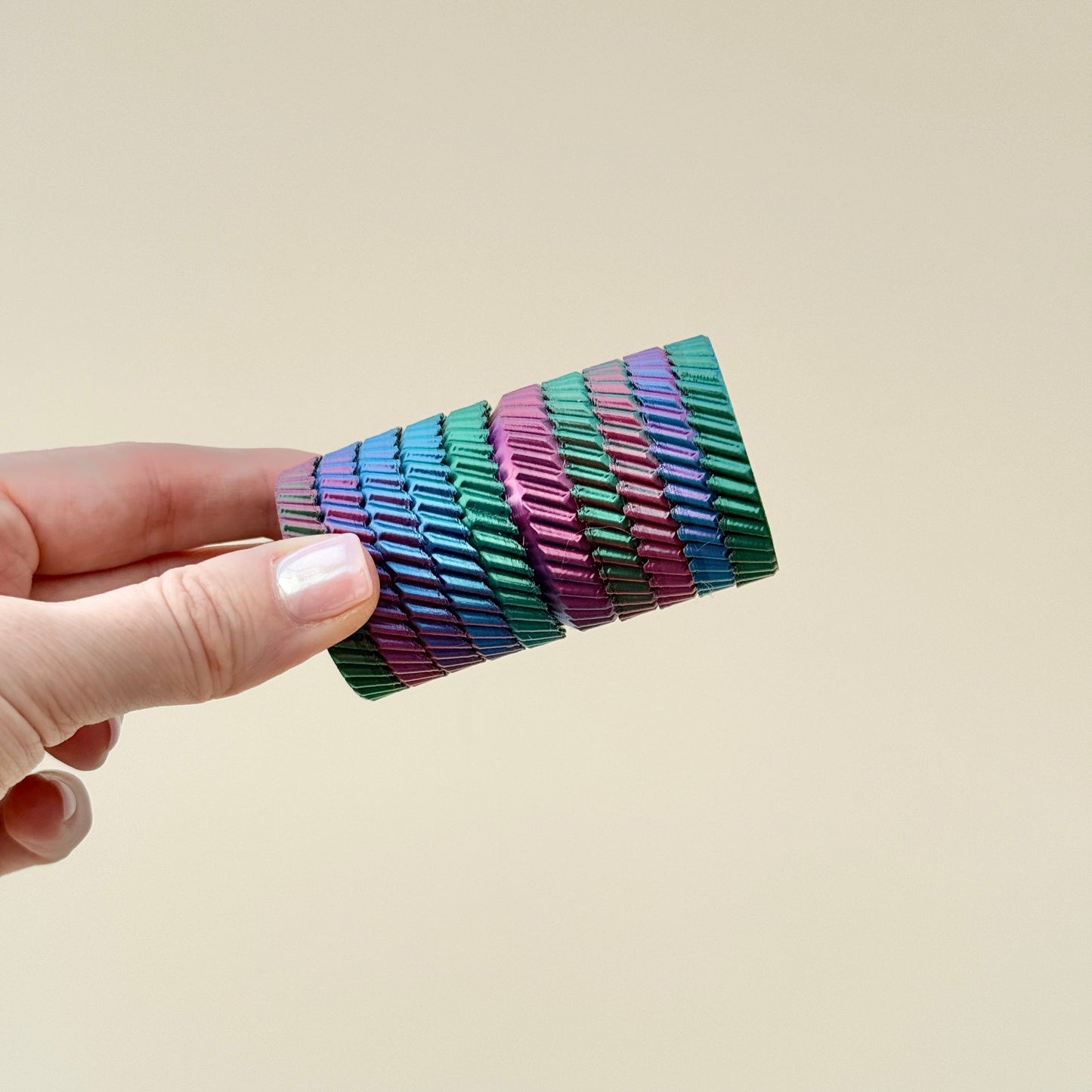 A stackable rainbow fidget toy featuring multiple spinning layers for sensory play.