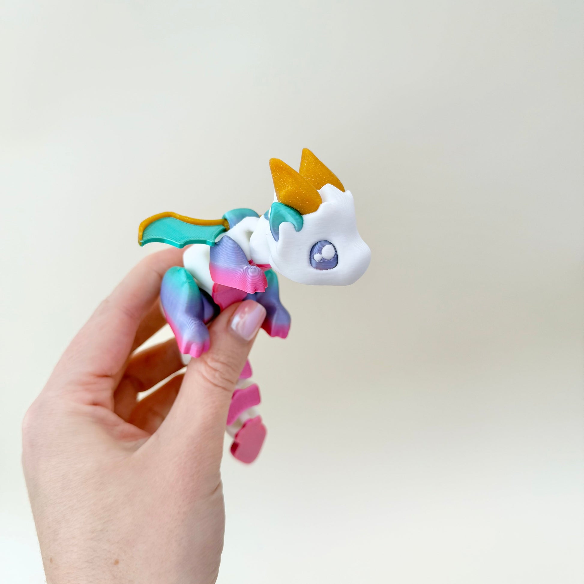 Choice of bright rainbow with gold horns or greyscale shadow with teal horns; fully articulated body.
