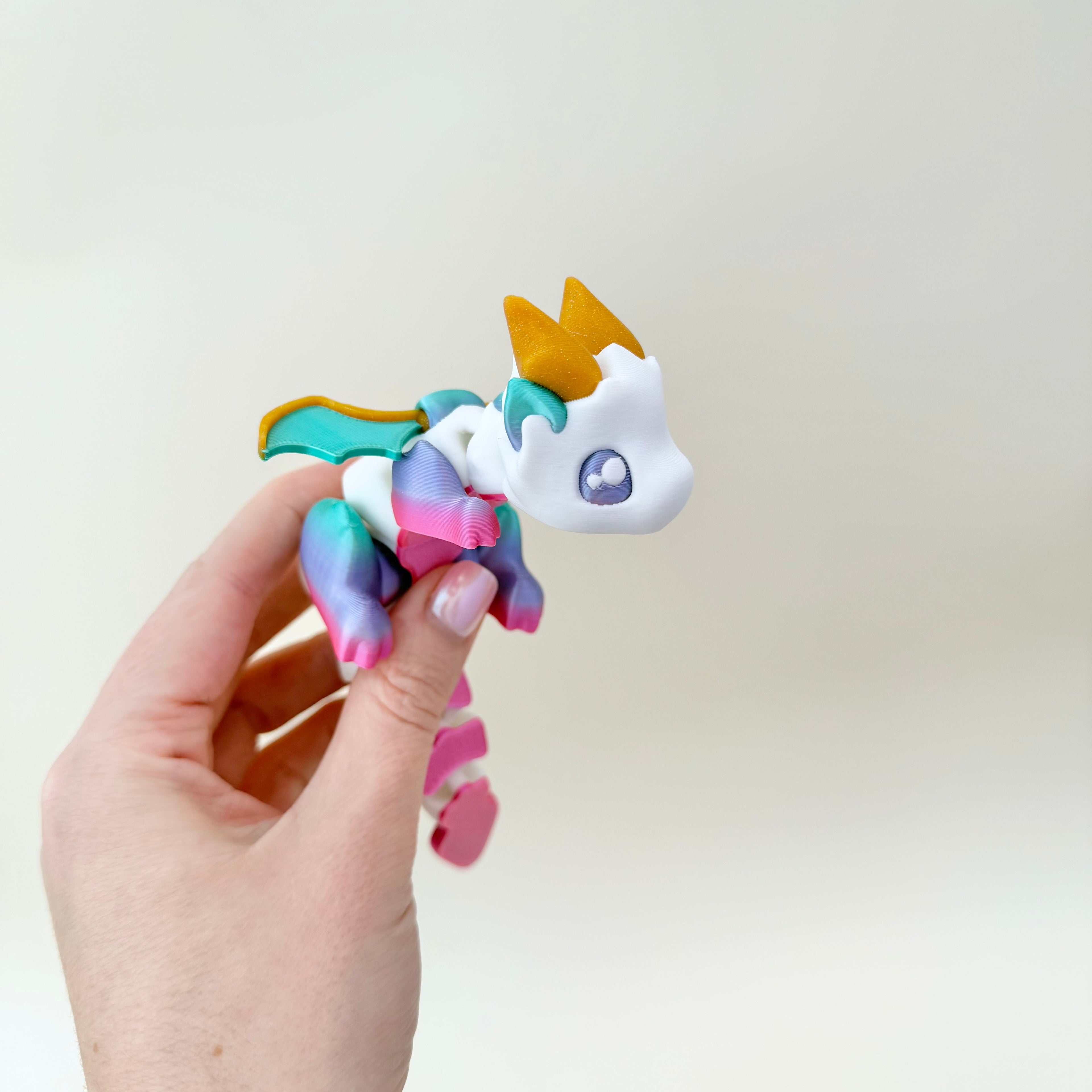 Choice of bright rainbow with gold horns or greyscale shadow with teal horns; fully articulated body.
