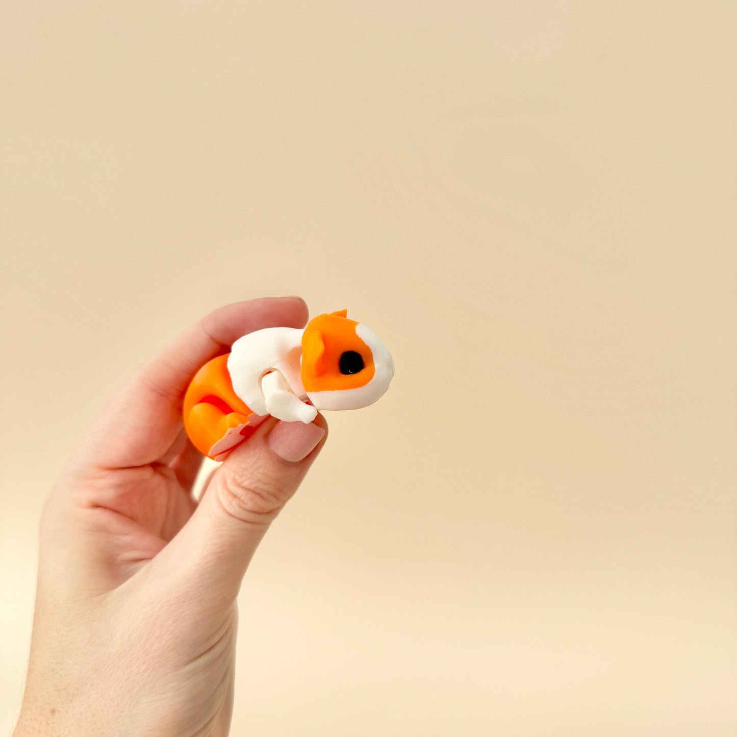 A realistic guinea pig fidget toy featuring articulated movement and a choice of black/white or ginger/white colour options.