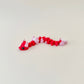Compact red-and-pink articulated snake fidget with soft texture and heart tail; great pocket sensory tool for fidgeters.
