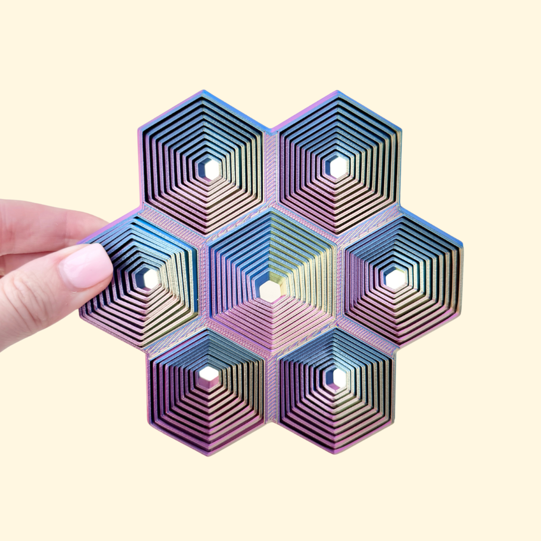 13 cm geometric desk fidget with moving concentric hex rings that ripple across the grid.
