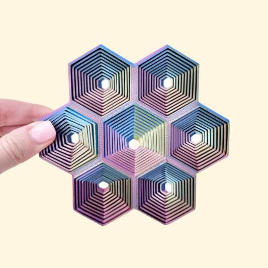 13 cm geometric desk fidget with moving concentric hex rings that ripple across the grid.
