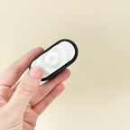 Sensory Ripple Click in black and white with ripple-textured clicker surface and ridged grip.