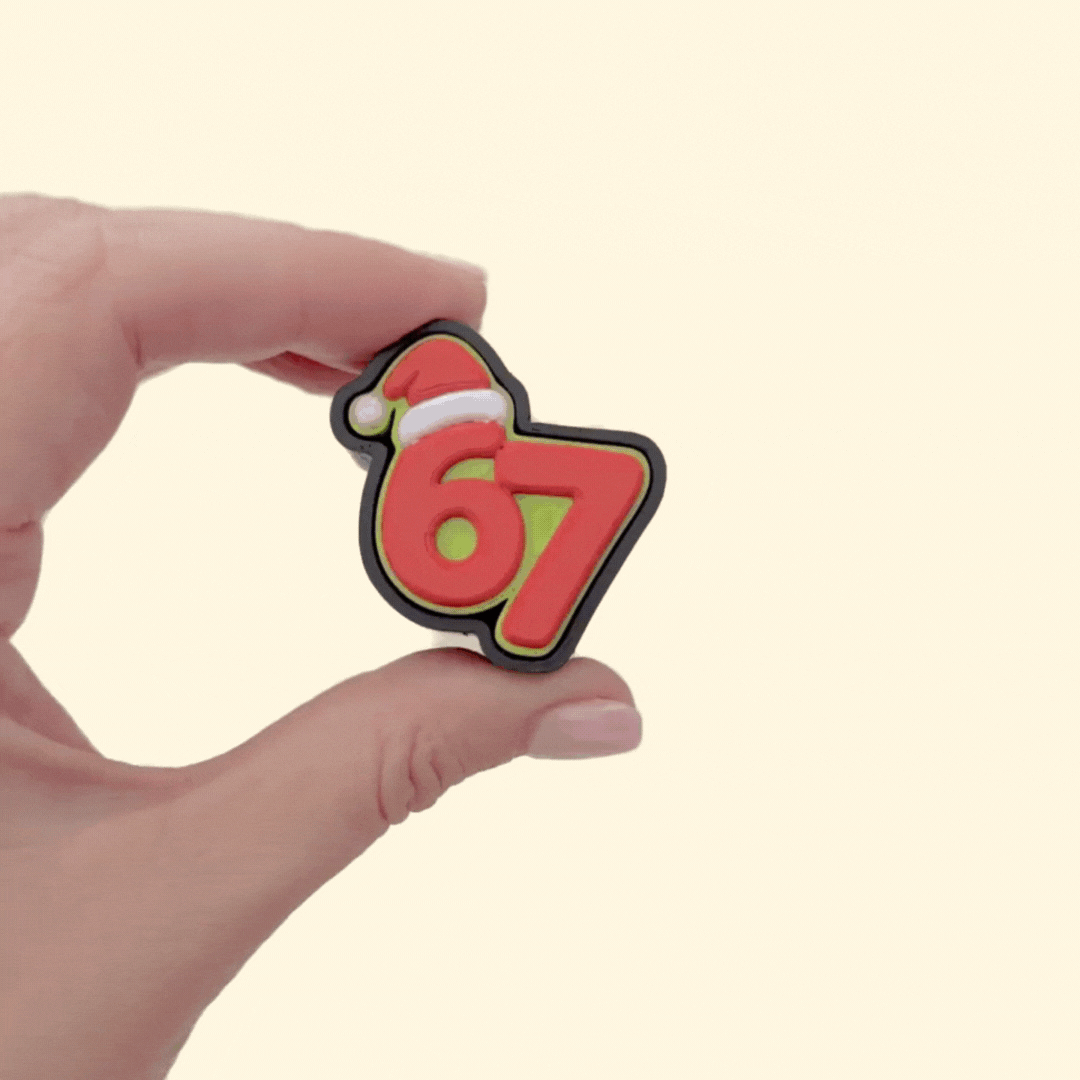 Bold red and green 67 desk fidget; tactile press action with smooth/raised details and keyring holes.
