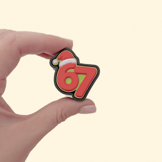 Bold red and green 67 desk fidget; tactile press action with smooth/raised details and keyring holes.
