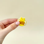 A handheld bee-shaped clicker fidget, designed for tactile sensory stimulation.