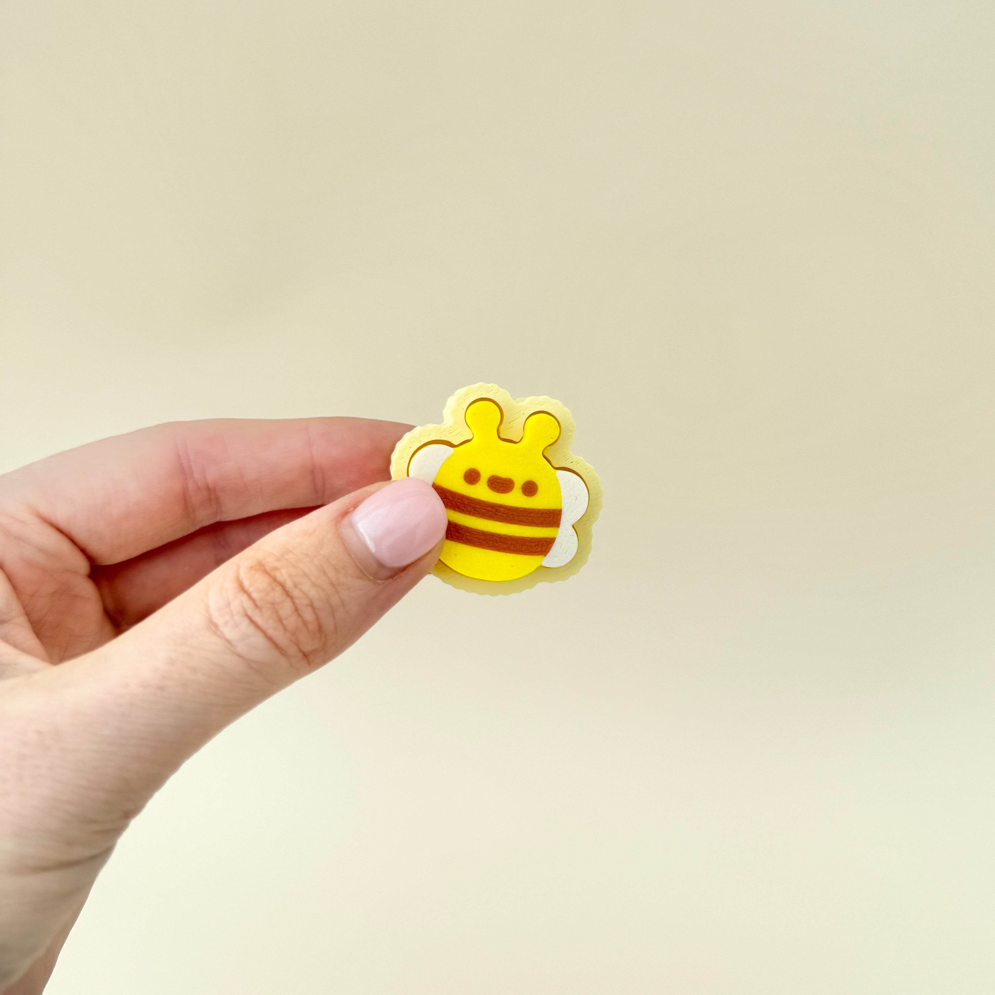 A handheld bee-shaped clicker fidget, designed for tactile sensory stimulation.