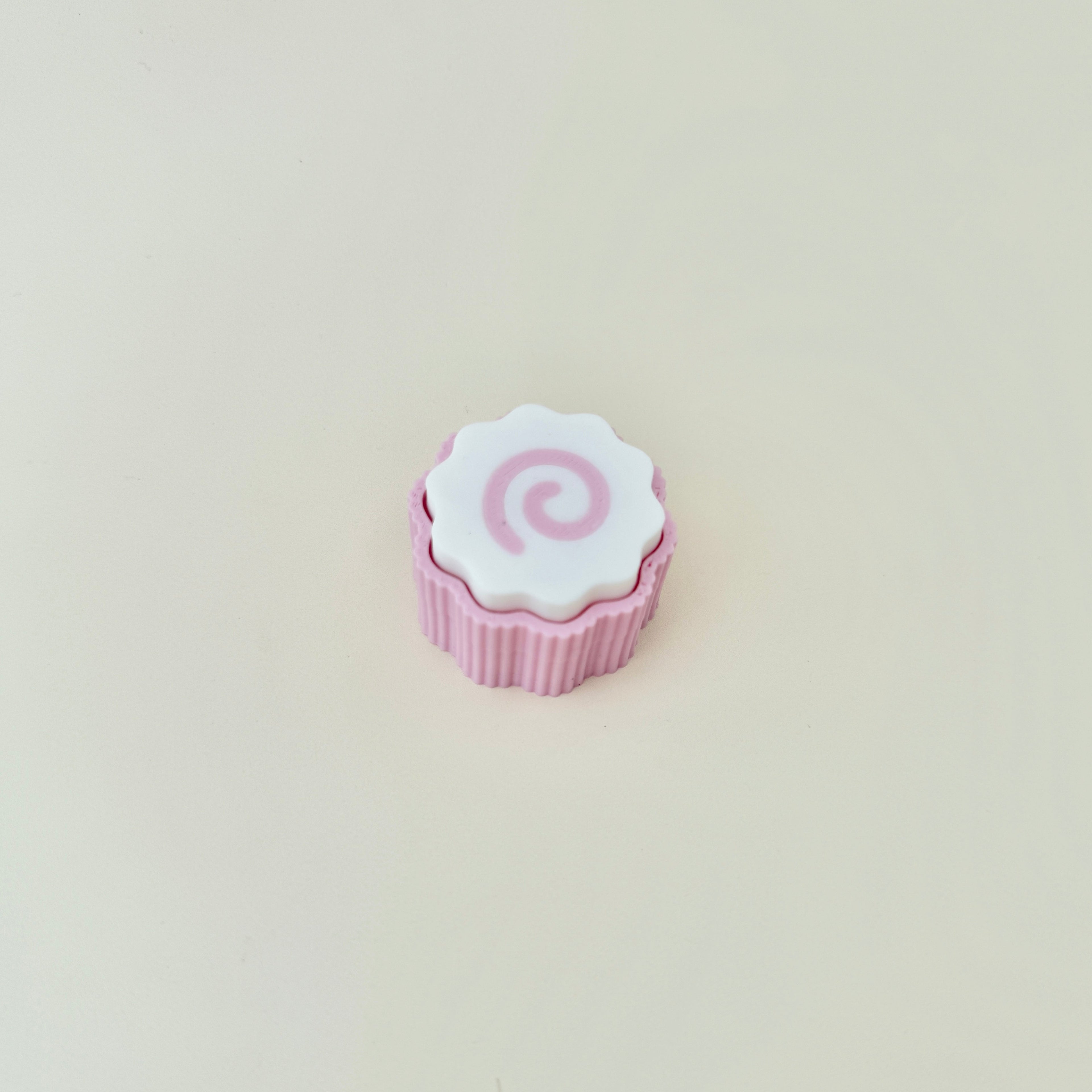 Small sensory clicker with a ribbed base and swirl top.