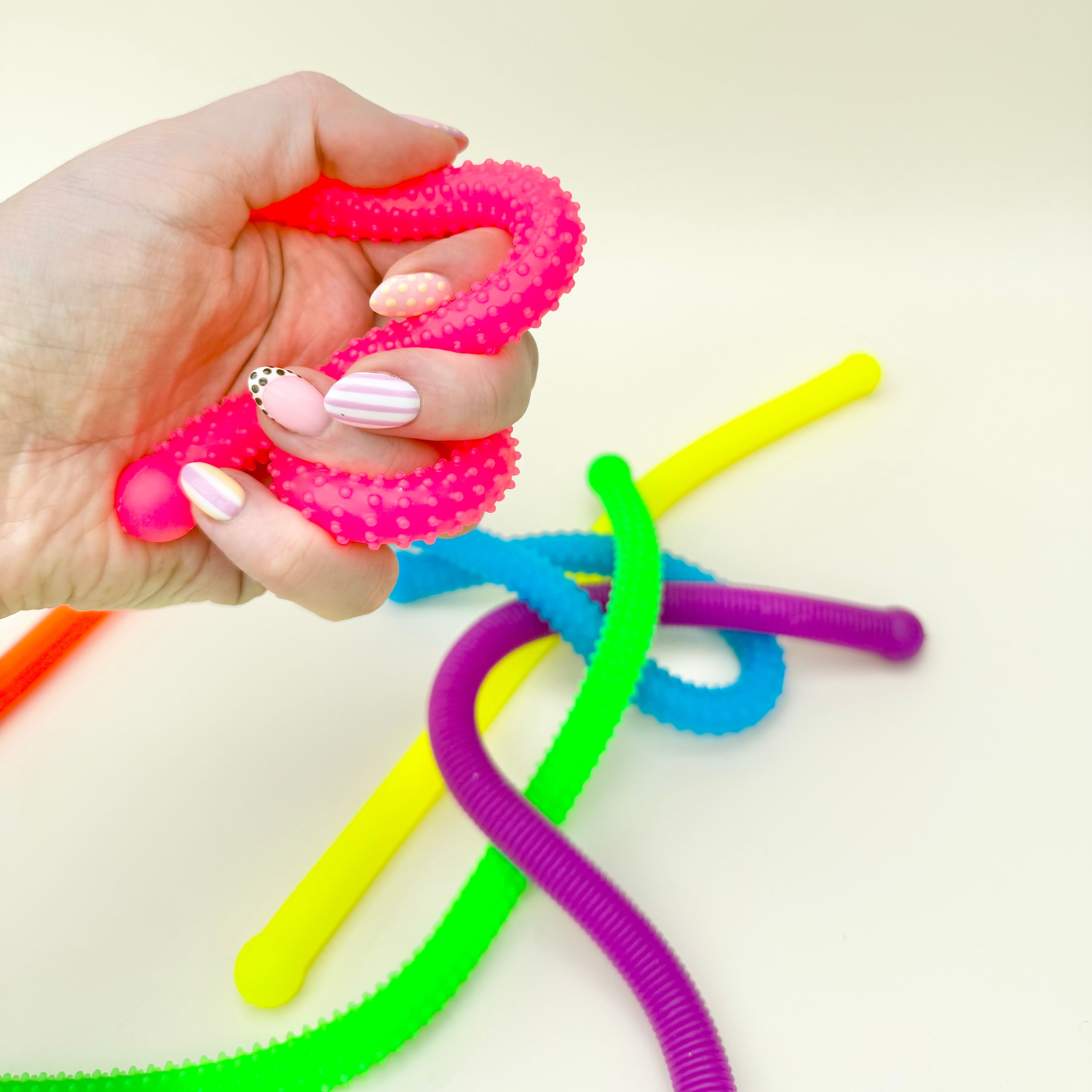 Textured stretch fidget noodles designed for tactile play, grounding and keeping hands occupied without noise.
