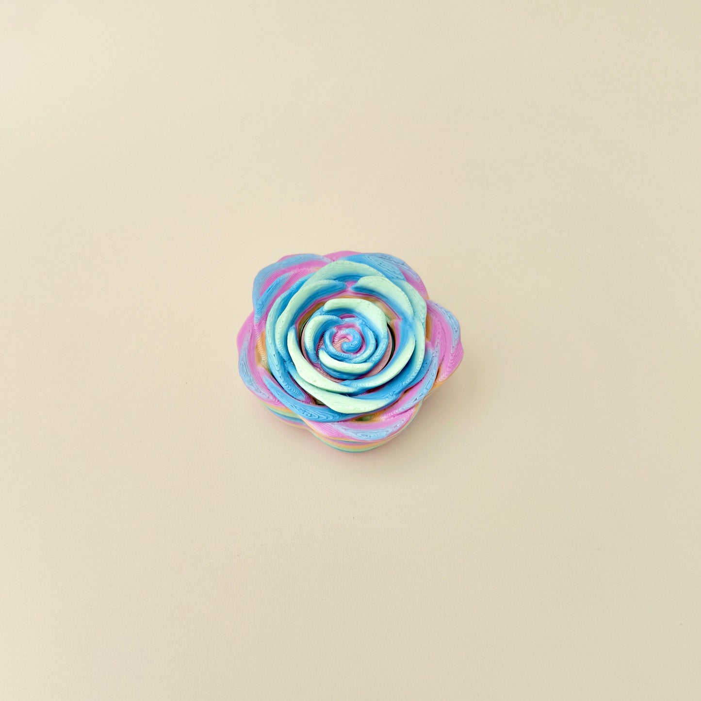 A sensory spinner toy featuring a rose shape with smooth rainbow colouring.