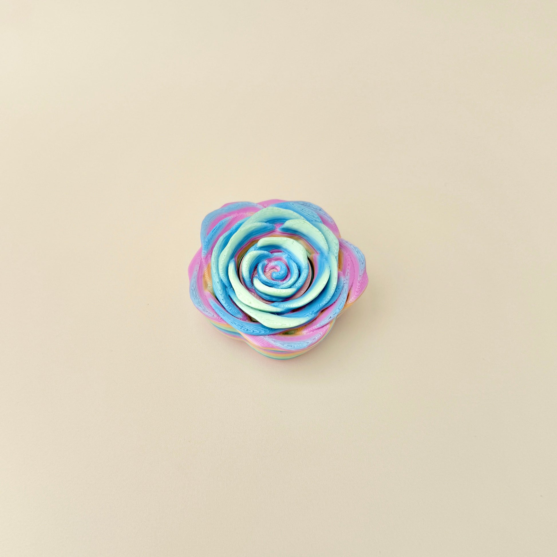 A sensory spinner toy featuring a rose shape with smooth rainbow colouring.