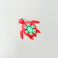 A red fidget toy shaped like a turtle with a strawberry-themed shell featuring white spots and a green pattern.