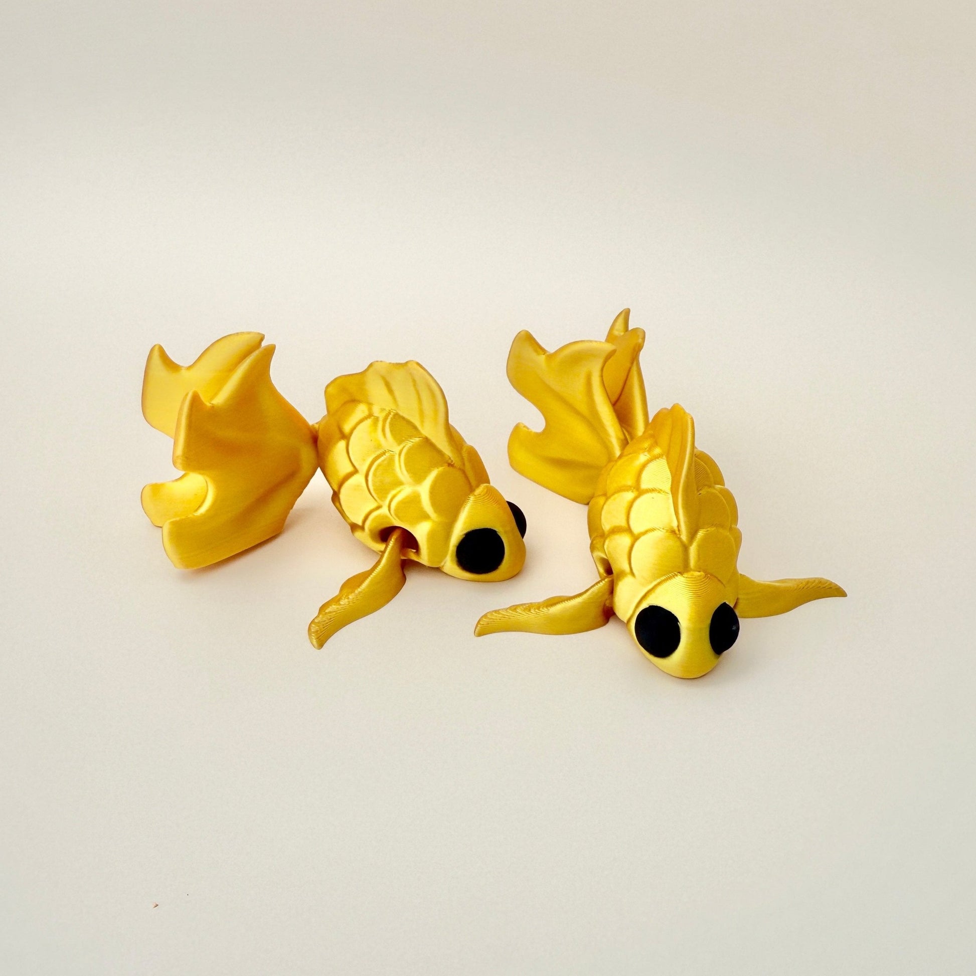 Goldfish fidget toy with a silk gold finish, big black eyes, and detailed texture, perfect for sensory play.