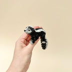 A black, grey, and white skunk toy with a flexible body, designed for fidgeting and sensory engagement.