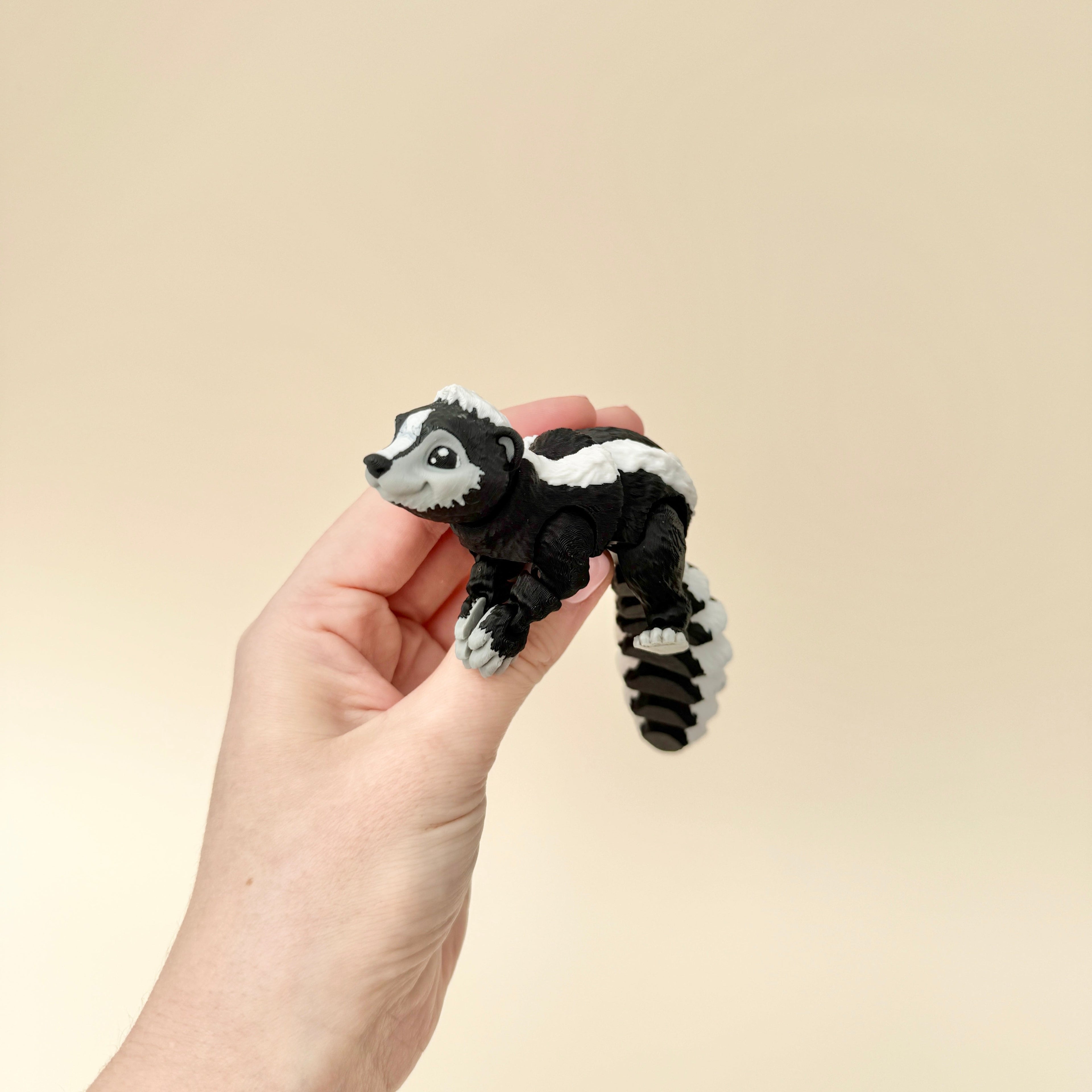 A black, grey, and white skunk toy with a flexible body, designed for fidgeting and sensory engagement.