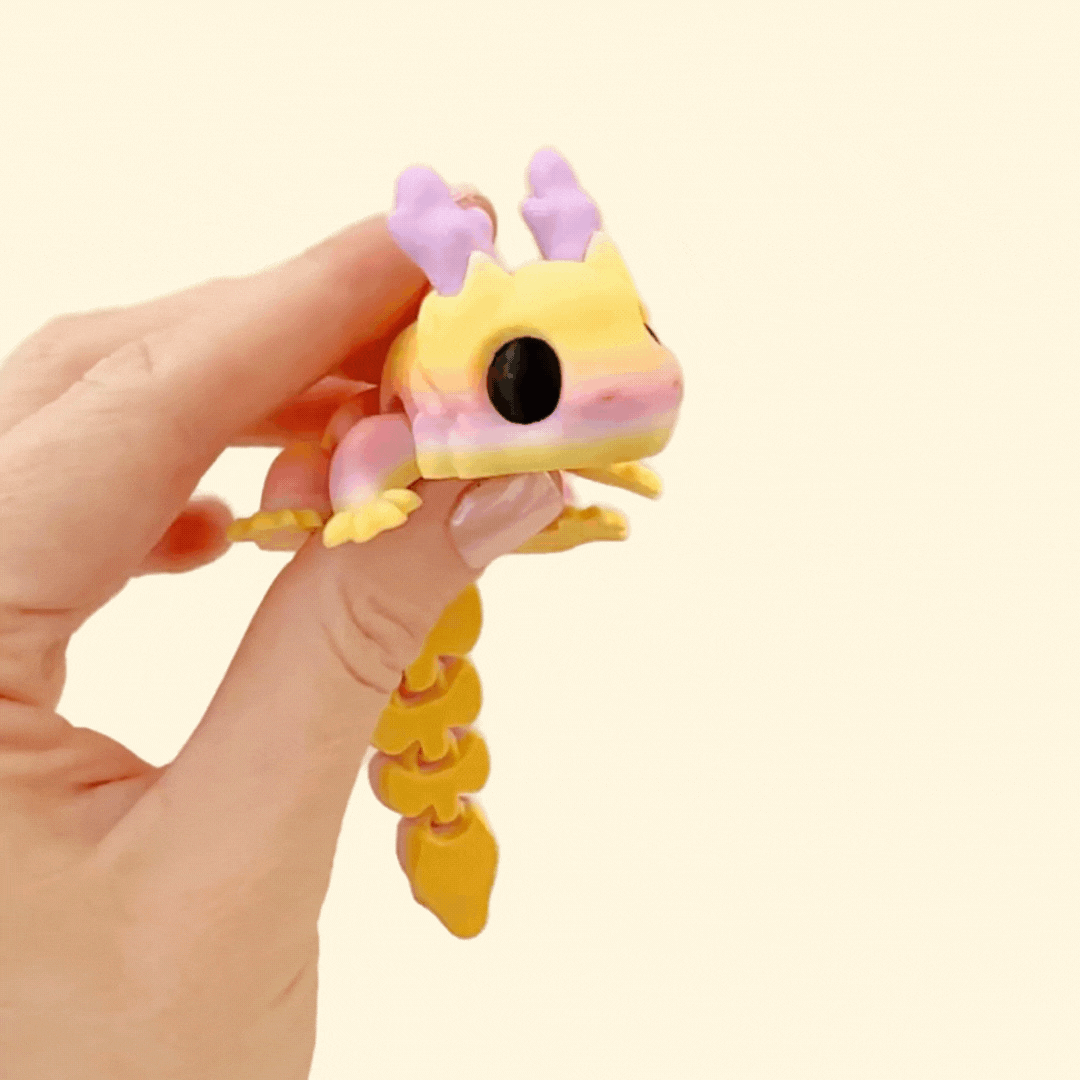 Fully articulated Skyburst Dragon fidget toy with sunrise tones of lilac, yellow, and orange, peach scales, and big black eyes.