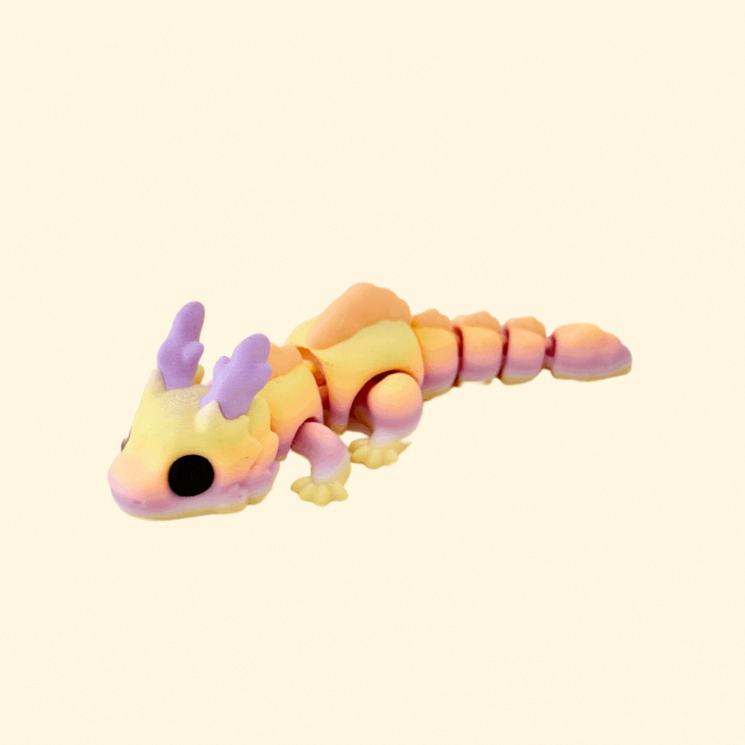 Skyburst Dragon fidget toy with sunrise tones of lilac, yellow, and orange, peach scales, and big black eyes.