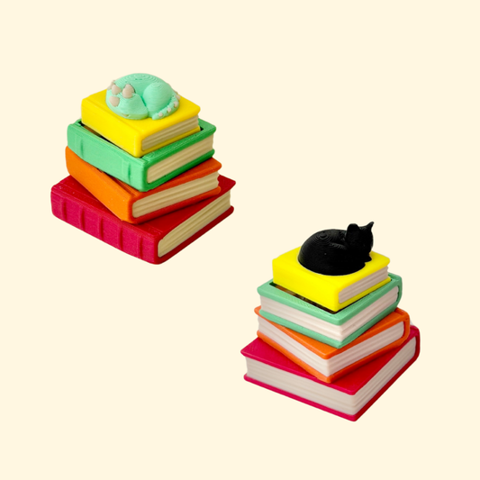 Curled cat on a tiny book pile that clicks when the top book is pressed.
