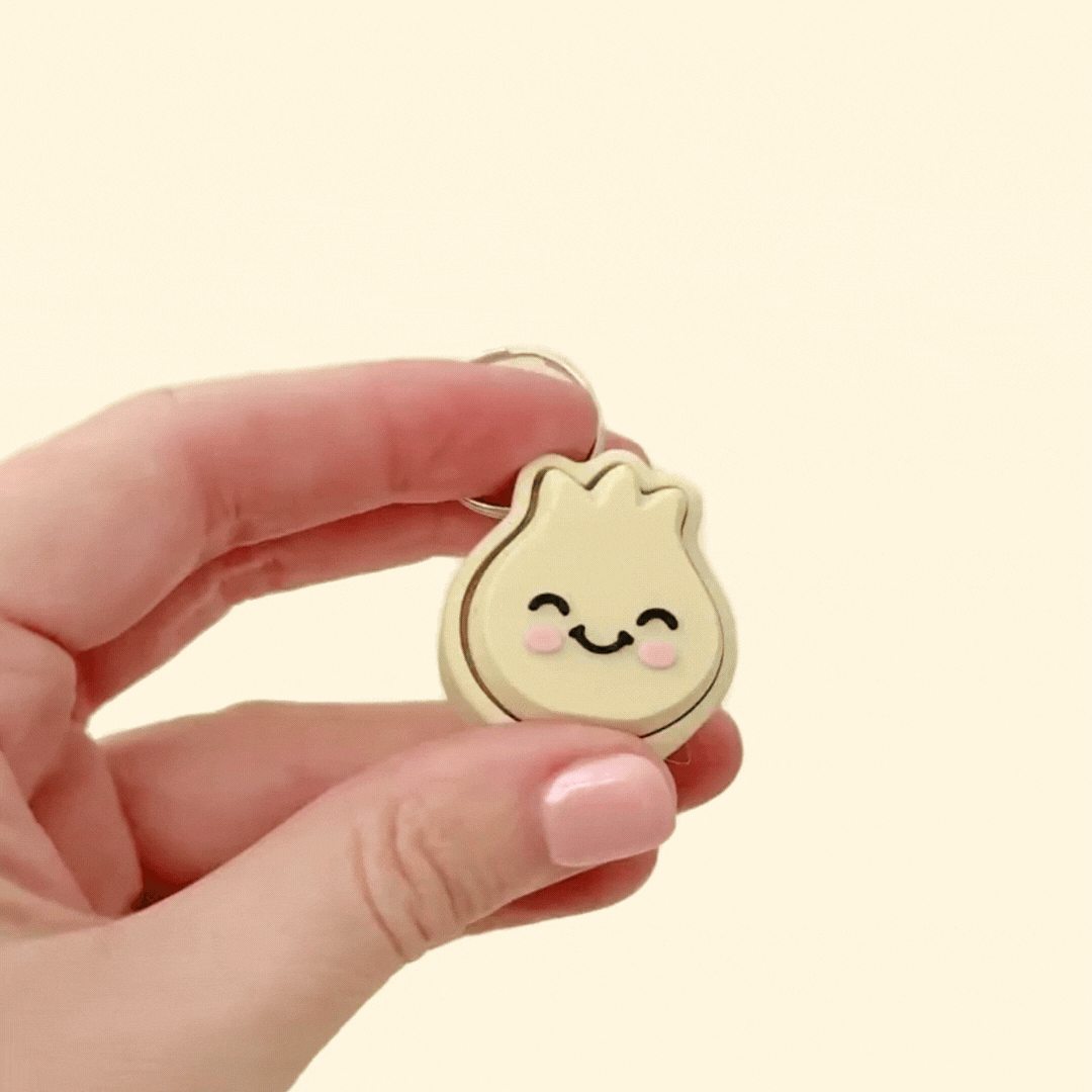 A beige dumpling clicker with a smiling face and pink cheeks, perfect for sensory play, stress relief, and keychain attachment.