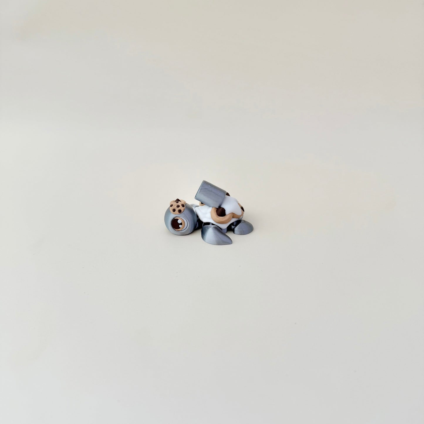 Compact 5 cm articulated turtle in metallic silver with textured cookie back; calming handheld fidget.
